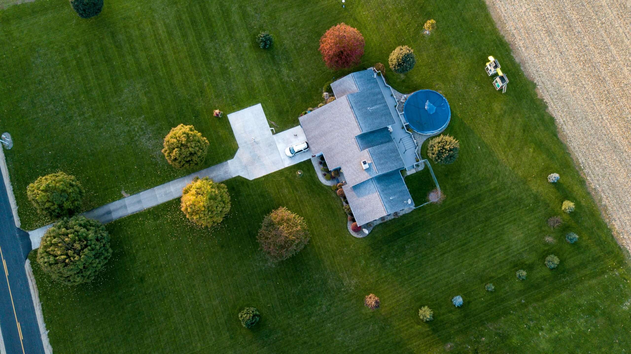 Aerial view of a suburban house with a pool, surrounded by green lawns and autumn trees, in Tipton, Indiana.